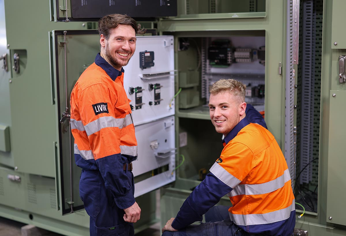 CE Group Electrical Contractor. Two men smiling at open switchboard